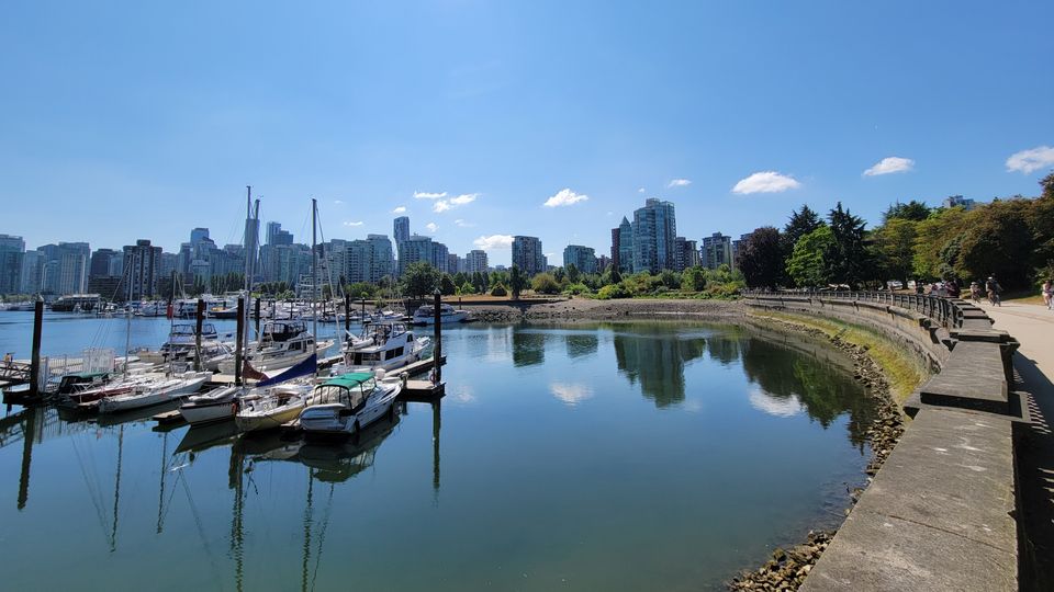 A walking path around a bay in Vancouver's downtown showcasing sailing boats and skyline on a clear day